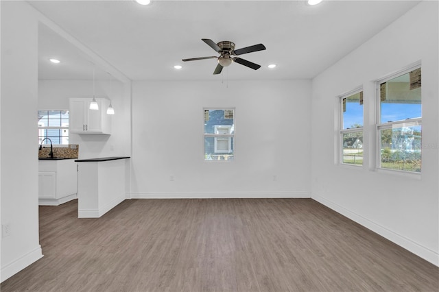 unfurnished living room with light hardwood / wood-style floors, sink, and ceiling fan