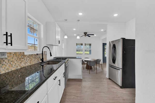 kitchen featuring white cabinetry, light wood-type flooring, dark stone countertops, and stainless steel fridge