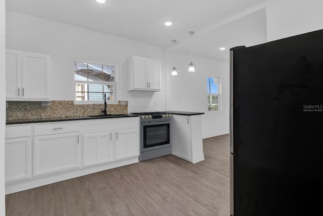 1020 W Line St, Leesburg, FL 34748 - kitchen with a sink, appliances with stainless steel finishes, dark countertops, white cabinets, and light wood-style flooring