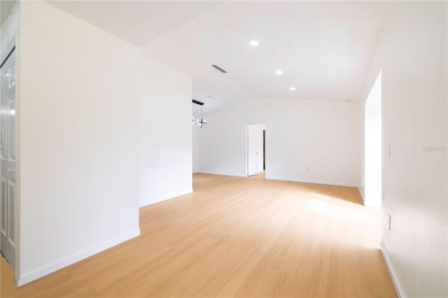 unfurnished room with a chandelier, light wood-type flooring, and lofted ceiling