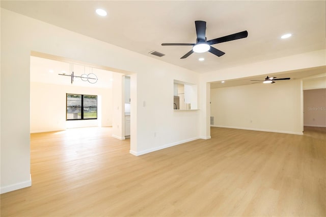 unfurnished room with ceiling fan with notable chandelier and light hardwood / wood-style floors