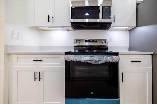 kitchen featuring stainless steel appliances, white cabinetry, and light stone counters