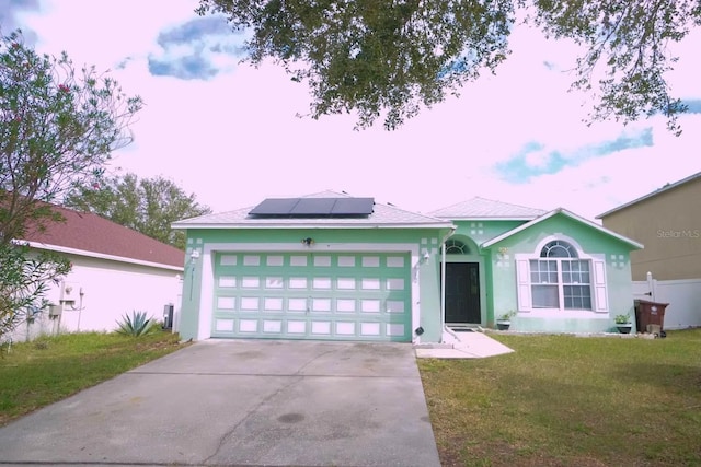 ranch-style house with solar panels, a garage, and a lawn