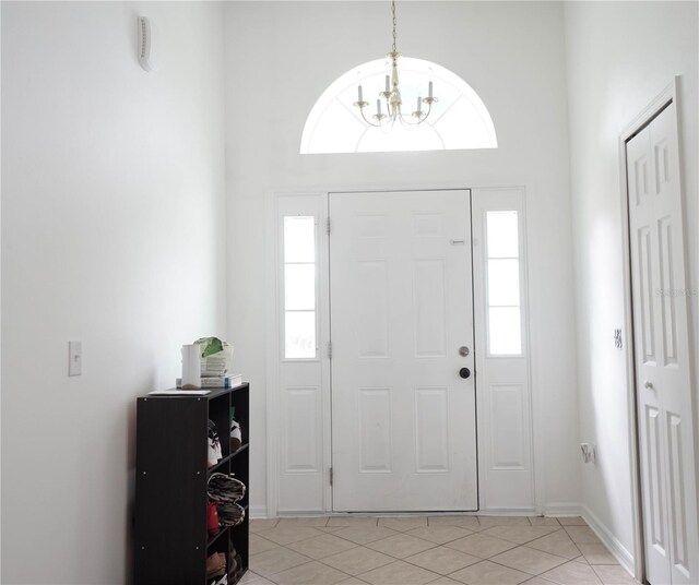 tiled foyer entrance with an inviting chandelier