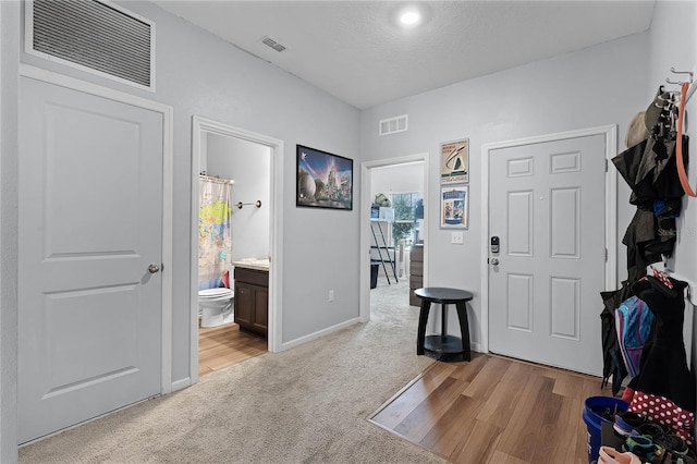 foyer with a textured ceiling and light carpet