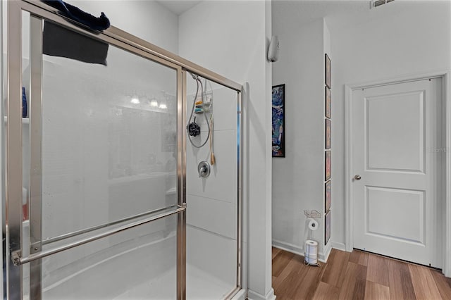 bathroom featuring hardwood / wood-style floors and a shower with door