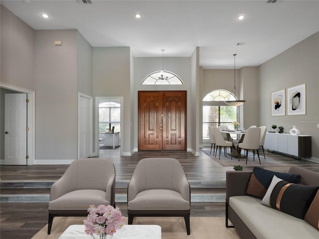 living room featuring a towering ceiling, hardwood / wood-style floors, and a healthy amount of sunlight