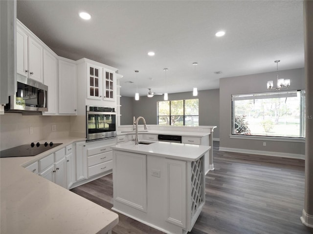 kitchen with a center island with sink, white cabinets, sink, appliances with stainless steel finishes, and decorative light fixtures