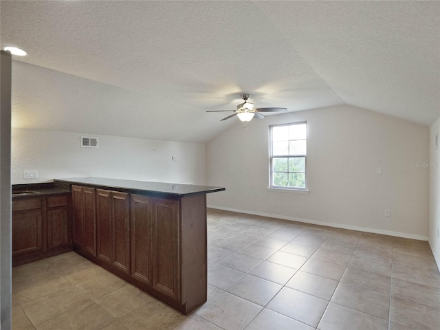 kitchen featuring kitchen peninsula, a textured ceiling, lofted ceiling, and ceiling fan