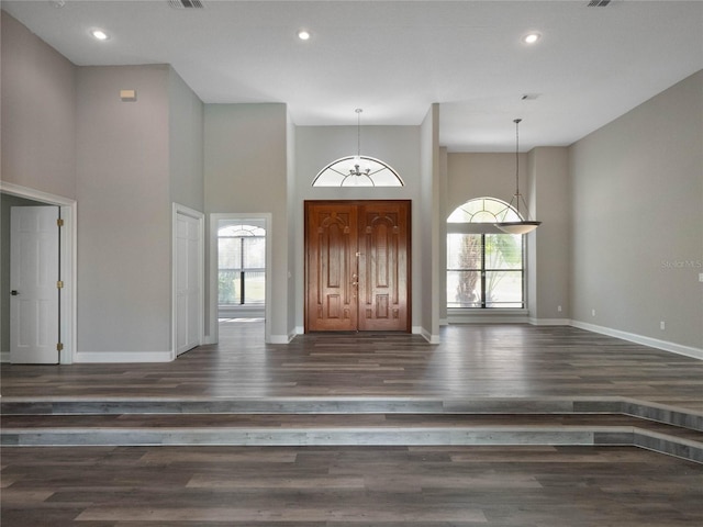 foyer entrance featuring a high ceiling, a chandelier, plenty of natural light, and dark hardwood / wood-style flooring