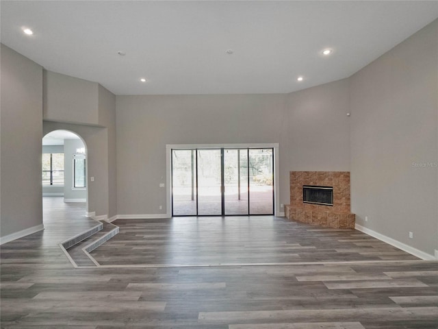 unfurnished living room with a fireplace, a towering ceiling, and hardwood / wood-style flooring