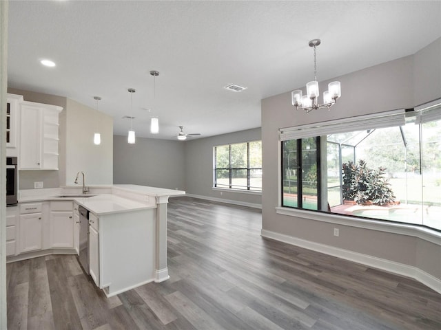 kitchen featuring sink, kitchen peninsula, hanging light fixtures, white cabinets, and dark wood-type flooring