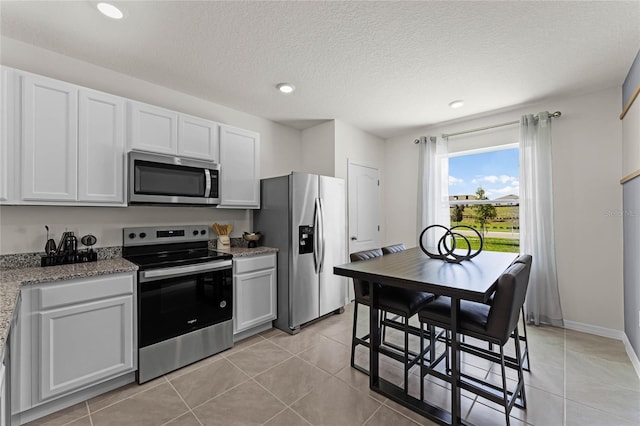 kitchen featuring a textured ceiling, white cabinets, stainless steel appliances, and light tile patterned floors