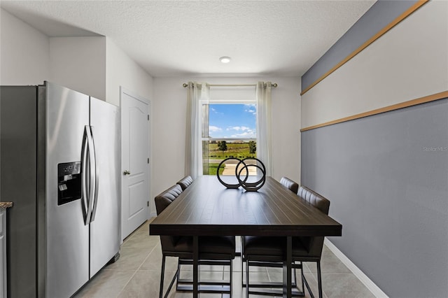 dining space with a textured ceiling and light tile patterned floors