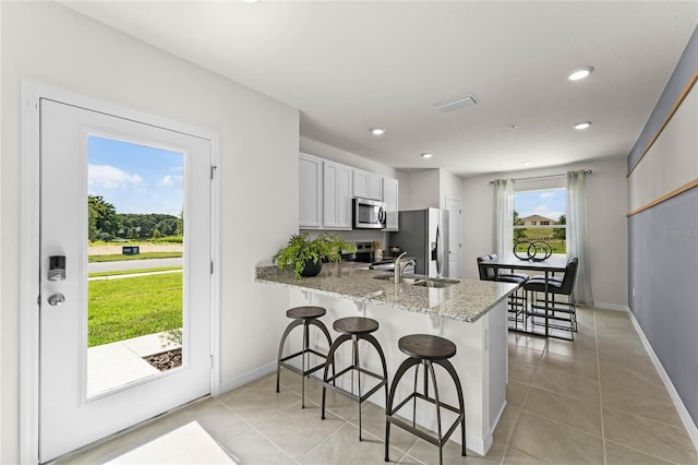 kitchen with kitchen peninsula, appliances with stainless steel finishes, plenty of natural light, and a kitchen breakfast bar