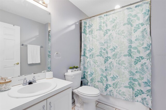 full bathroom featuring vanity, shower / bath combo with shower curtain, tile patterned flooring, and toilet
