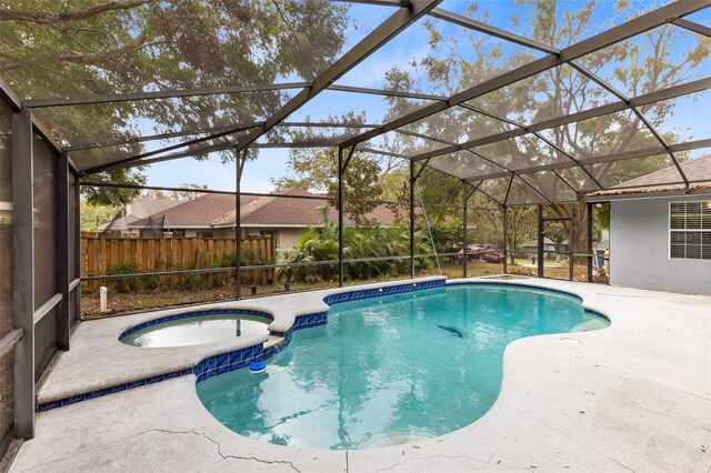view of pool with a patio area, glass enclosure, and an in ground hot tub