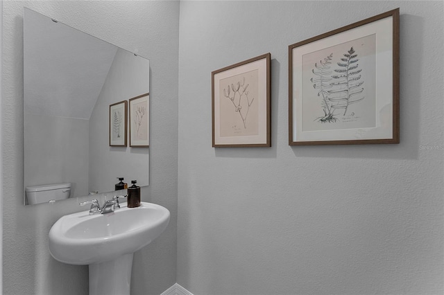 bathroom with sink, toilet, and lofted ceiling