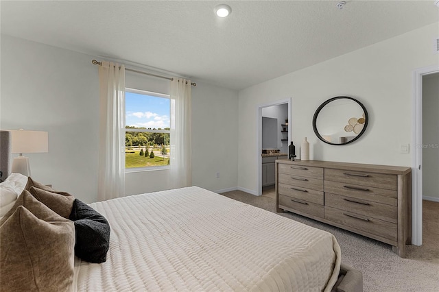 carpeted bedroom with a textured ceiling and ensuite bath