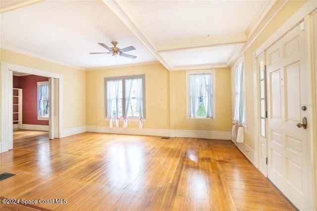 empty room with beamed ceiling, crown molding, wood-type flooring, and ceiling fan