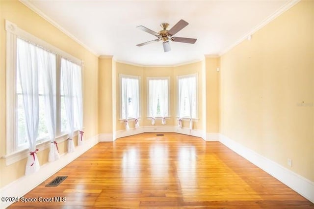 spare room with a wealth of natural light, crown molding, light hardwood / wood-style flooring, and ceiling fan