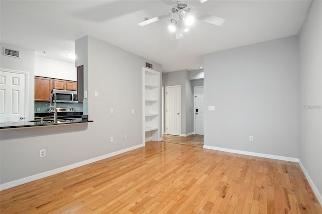 unfurnished living room featuring light hardwood / wood-style floors, sink, and ceiling fan