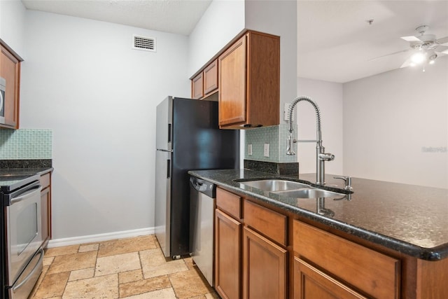 kitchen with decorative backsplash, stainless steel appliances, dark stone countertops, sink, and ceiling fan