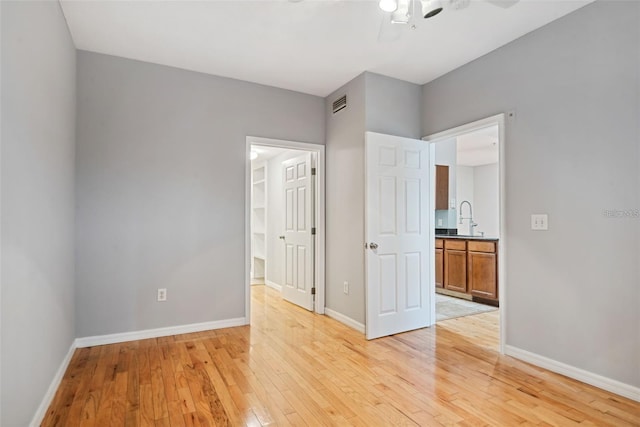 empty room with sink, light wood-type flooring, and ceiling fan