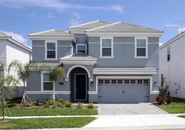 mediterranean / spanish-style home featuring a garage and a front lawn