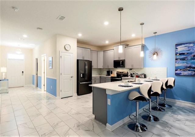 kitchen with stainless steel appliances, backsplash, pendant lighting, a breakfast bar area, and kitchen peninsula