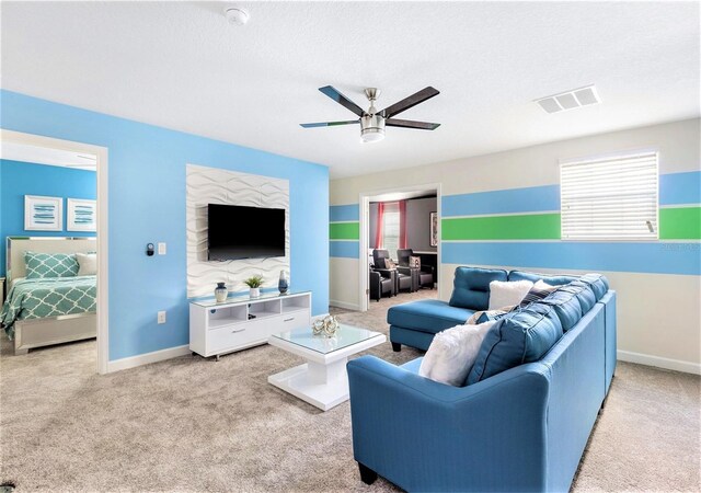 living room with a textured ceiling, carpet, and ceiling fan