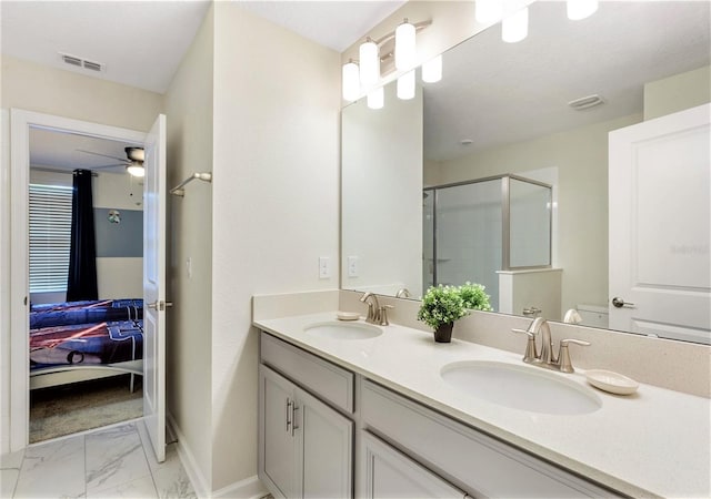 bathroom with toilet, vanity, a shower with door, and ceiling fan