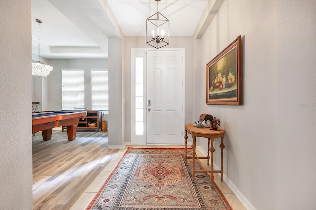 foyer entrance featuring pool table, a wealth of natural light, hardwood / wood-style flooring, and a notable chandelier