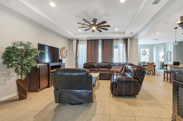 living room featuring light tile patterned floors, ceiling fan, and a raised ceiling