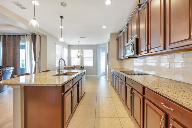 kitchen with a center island with sink, sink, tasteful backsplash, pendant lighting, and appliances with stainless steel finishes