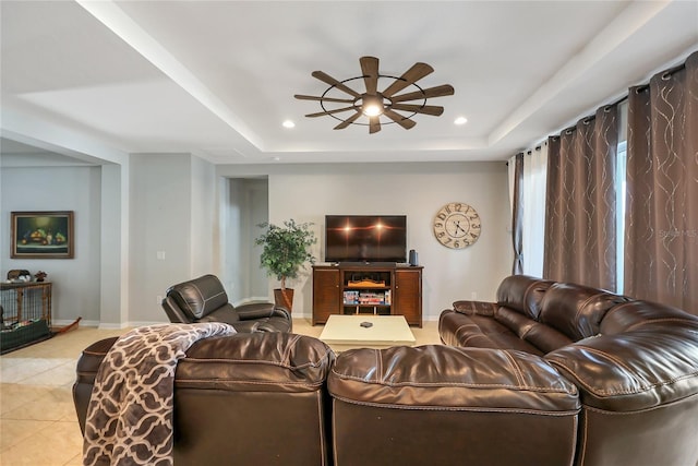 living room with ceiling fan, light tile patterned floors, and a tray ceiling