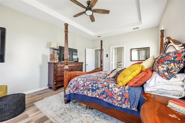 bedroom featuring light wood-type flooring, ceiling fan, and a raised ceiling