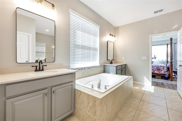 bathroom featuring tiled bath, tile patterned flooring, vanity, and a healthy amount of sunlight