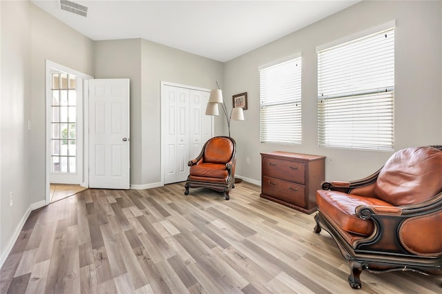 living area with light hardwood / wood-style floors and a healthy amount of sunlight