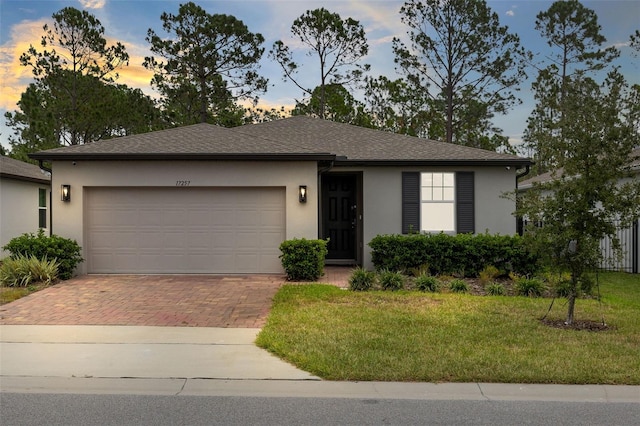 ranch-style home with a garage and a lawn