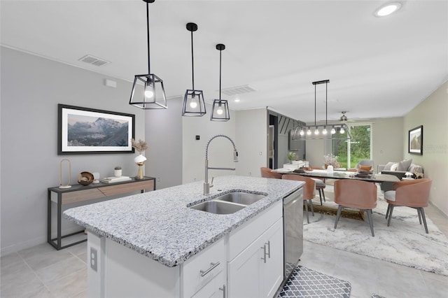 kitchen featuring sink, light stone countertops, decorative light fixtures, a kitchen island with sink, and white cabinets