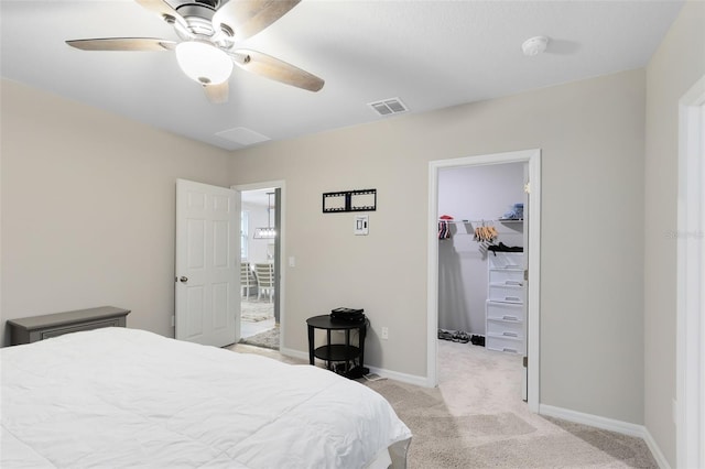 bedroom featuring ceiling fan, a closet, a walk in closet, and light colored carpet