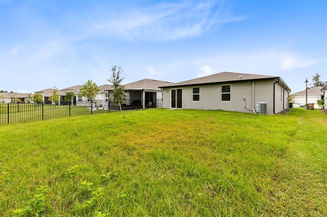 back of house with central AC unit and a yard