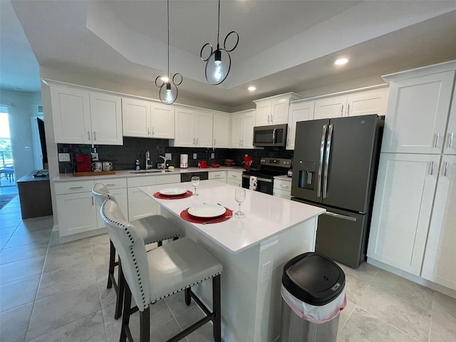 kitchen with tasteful backsplash, white cabinetry, decorative light fixtures, and stainless steel appliances