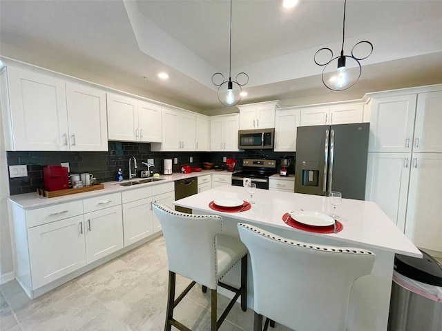 kitchen with stainless steel appliances, a breakfast bar area, white cabinetry, and decorative light fixtures