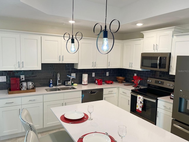 kitchen with white cabinetry, appliances with stainless steel finishes, hanging light fixtures, sink, and decorative backsplash