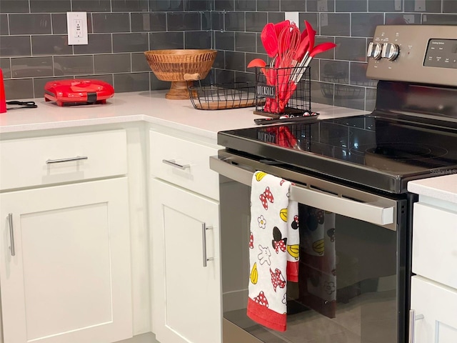 kitchen with white cabinets, stainless steel electric range oven, and tasteful backsplash