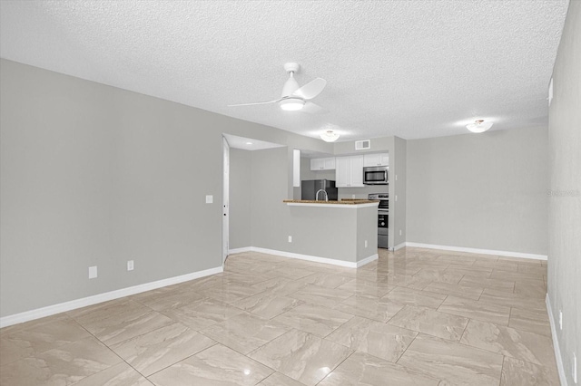 unfurnished living room featuring a textured ceiling and ceiling fan