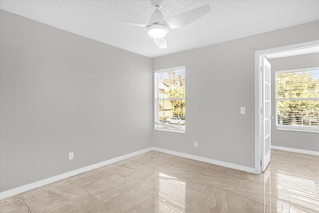 spare room with a textured ceiling, a healthy amount of sunlight, and ceiling fan