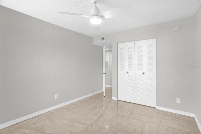 unfurnished bedroom with a textured ceiling, a closet, and ceiling fan